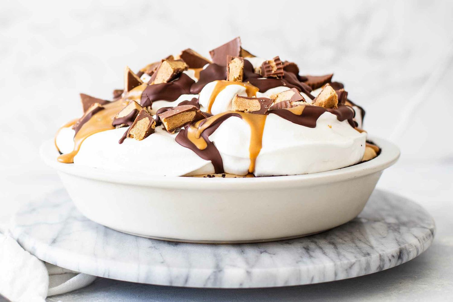 A whole Peanut butter pie topped with whipped cream and peanut butter cups.