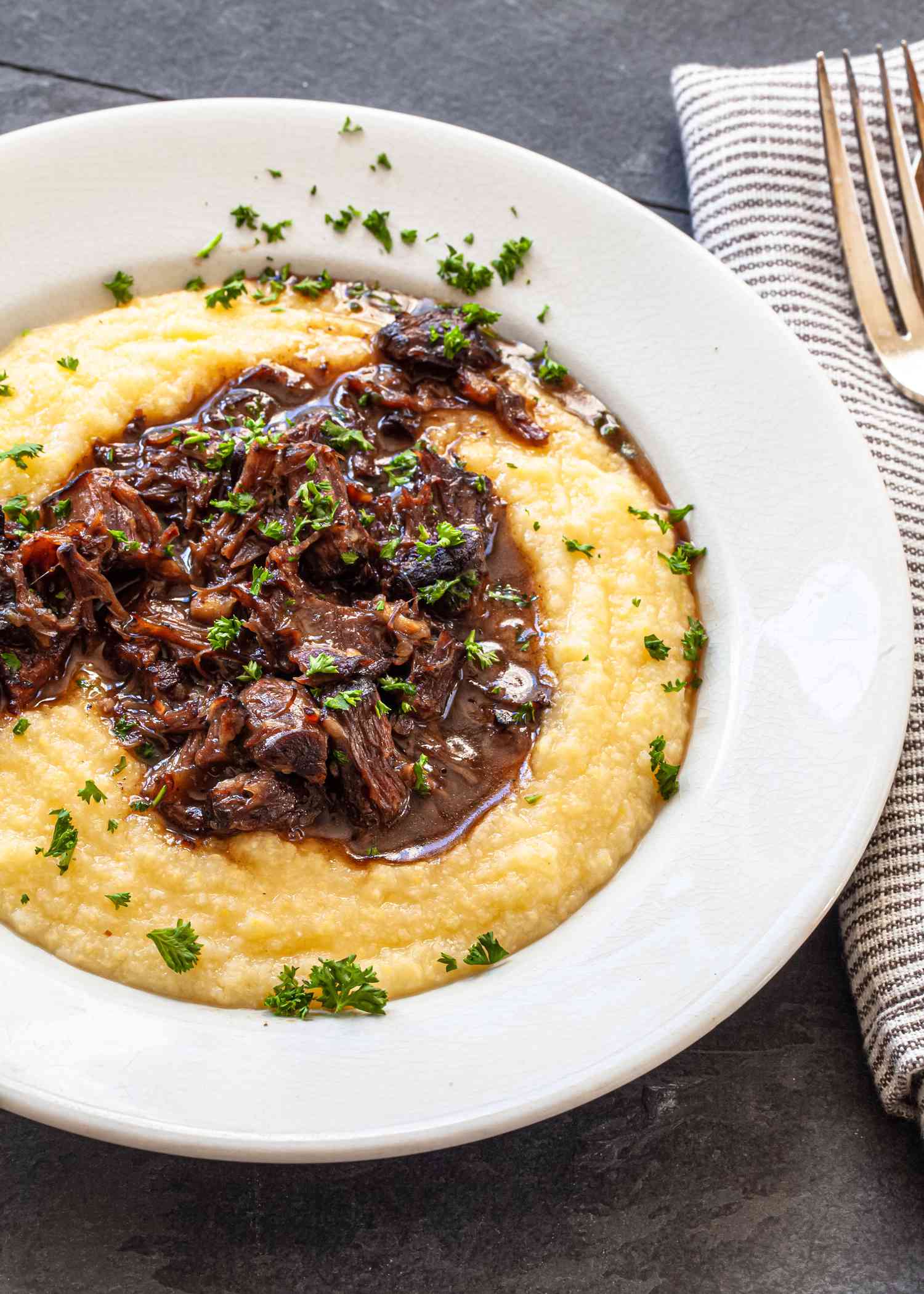 A bowl of grits and braised oxtails.