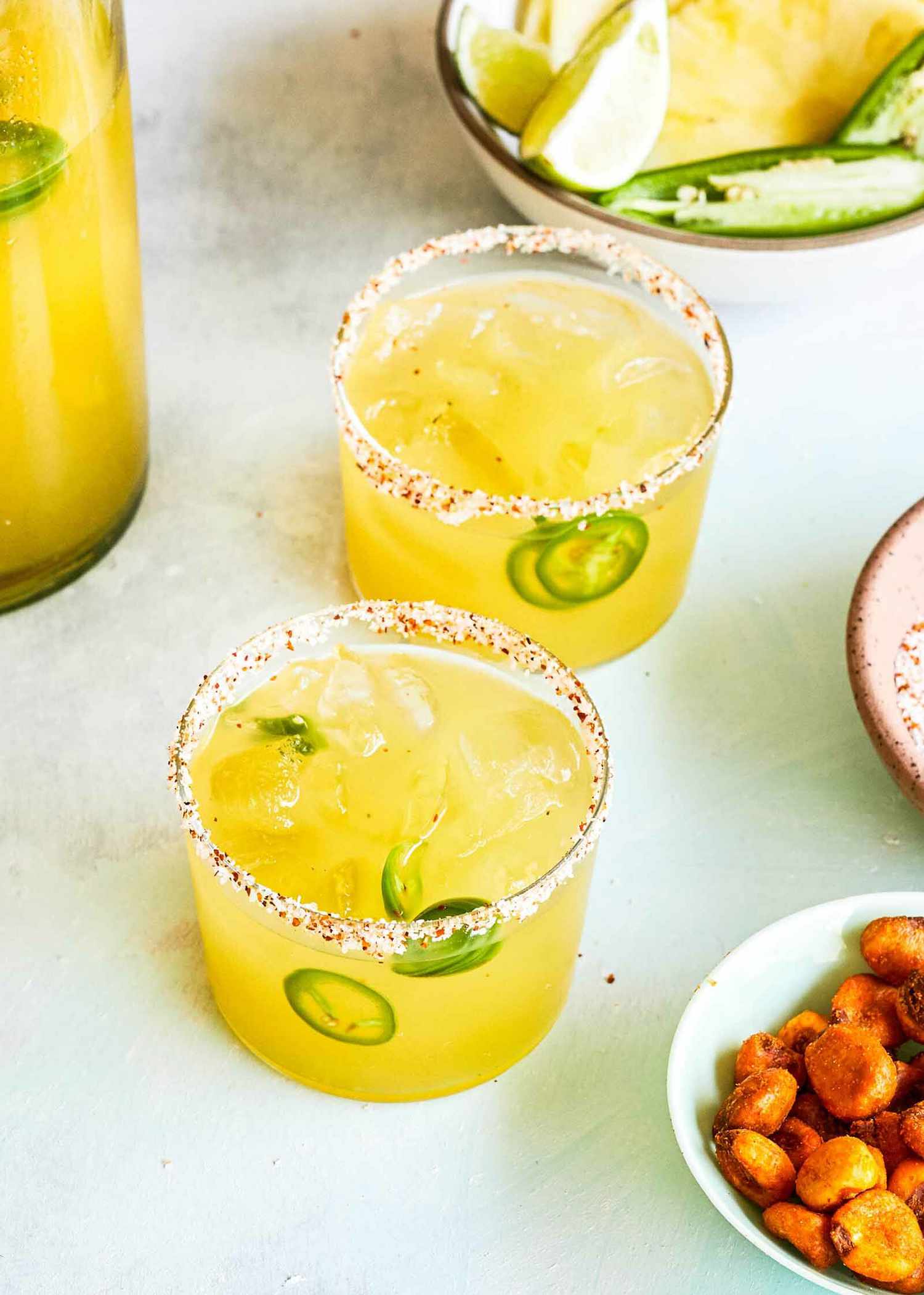 Pineapple Margaritas in two glasses garnishes with sliced jalapeno