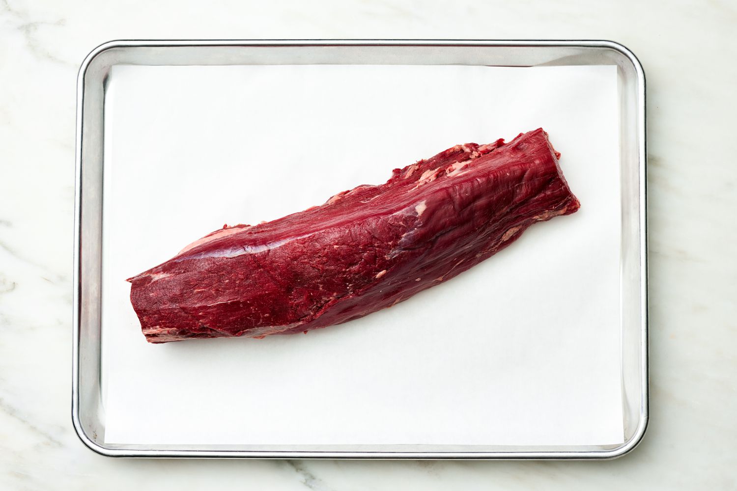 Fillet of Meat on a Parchment Paper Lined Baking Sheet