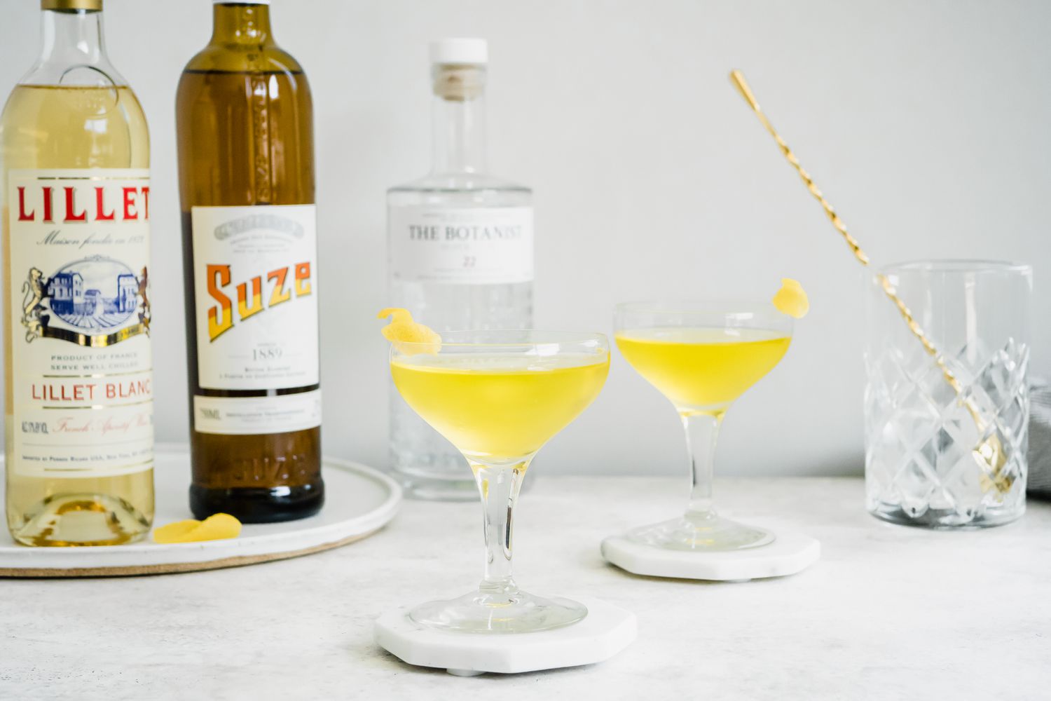 Glasses of White Negroni on Coasters Next to Ingredients