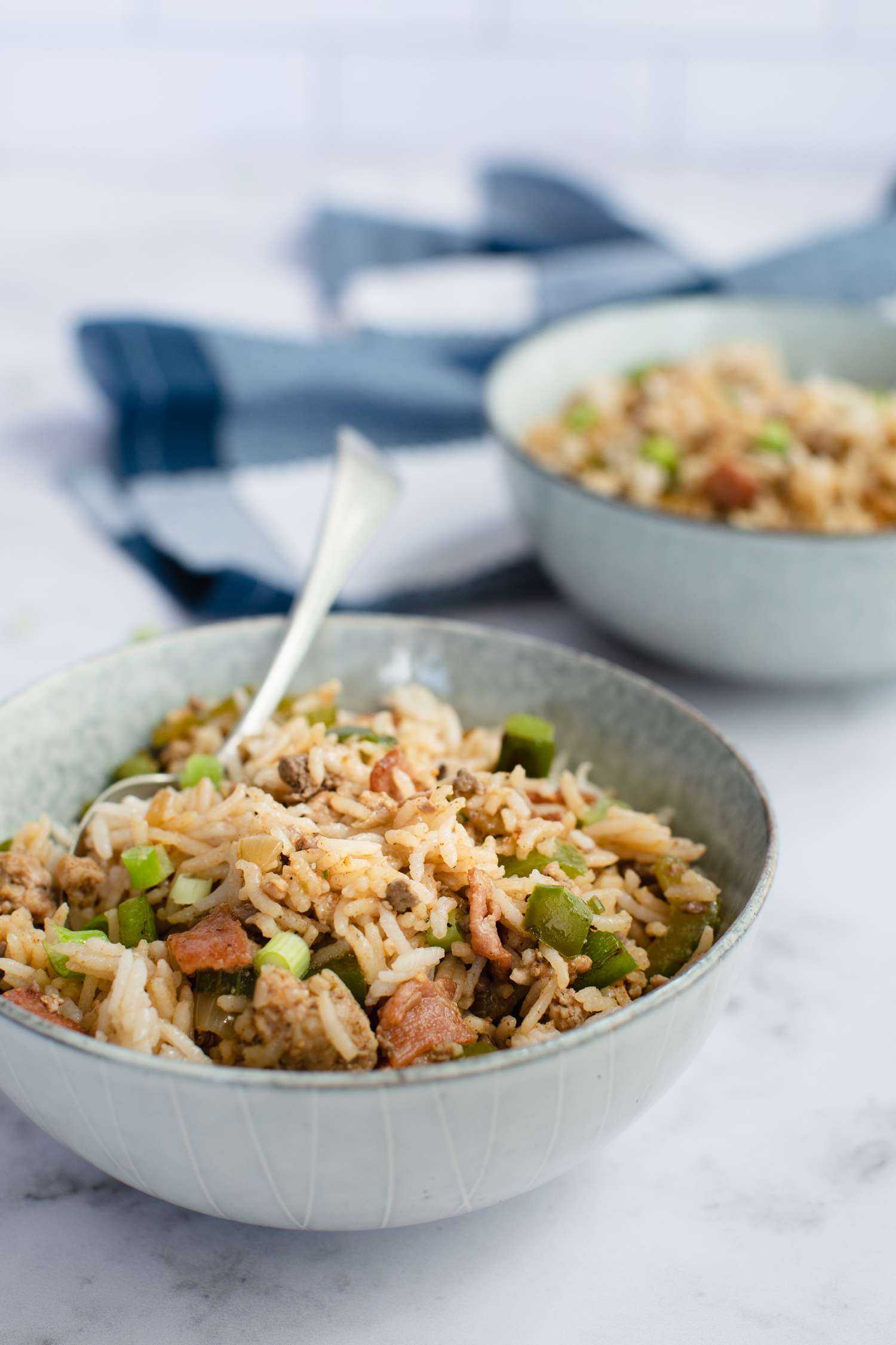 Side view of two bowls of Cajun Dirty Rice on a marble countertop.
