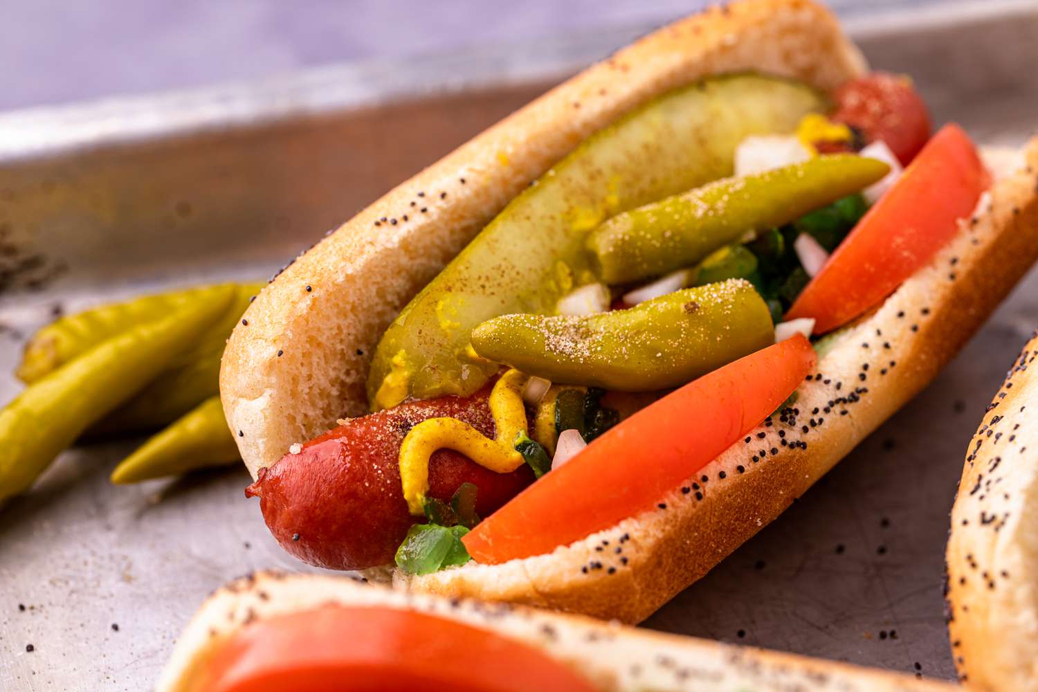 Chicago dogs with tomato and pickles on a pan.