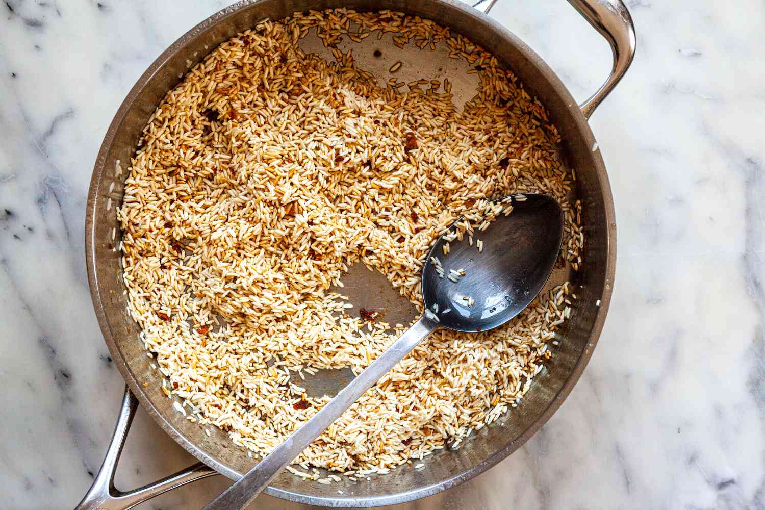 Browning the rice for an arroz con pollo recipe in a skillet.