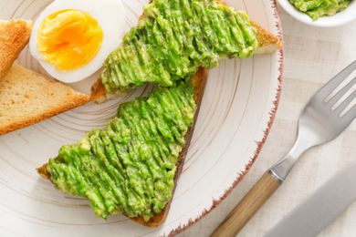 Avocado toast and a boiled half egg on a white plate