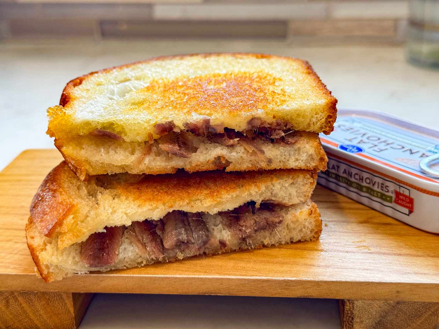 anchovy toast cut in half on a cutting board (cross-section facinf foward)