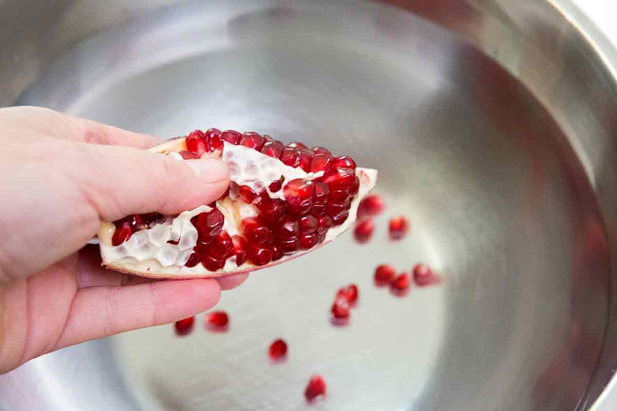 how to eat a pomegranate - removing seeds over bowl of water