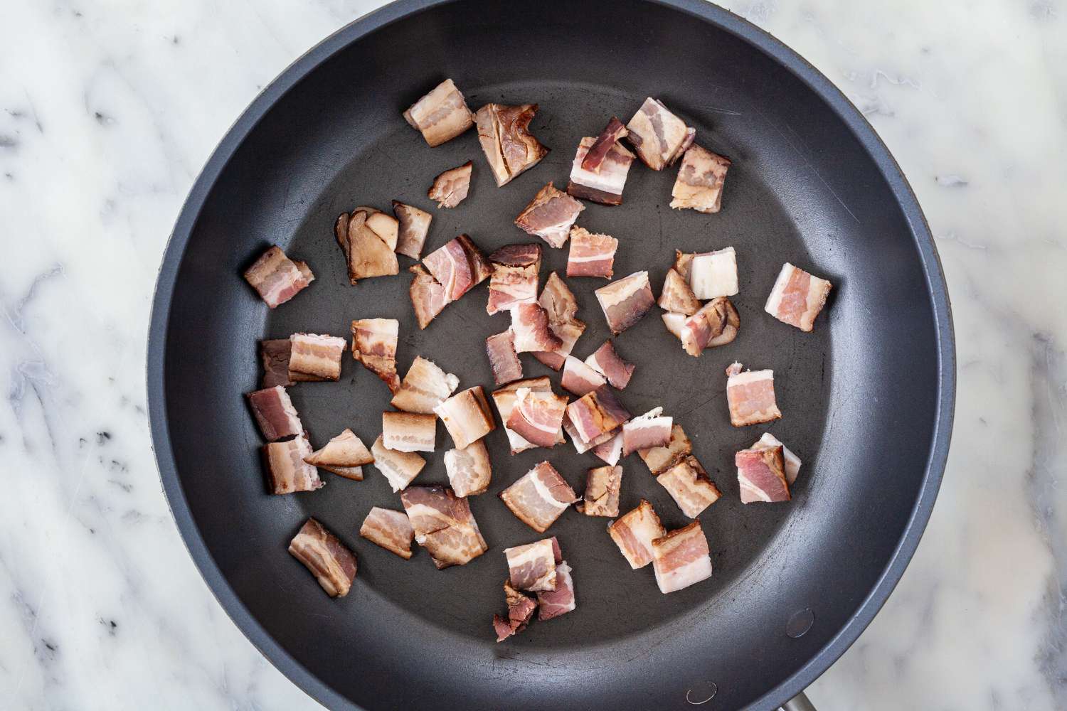 Chopped bacon cooking in a skillet for Spanish Style Migas.