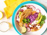 A plate of fish tacos with a glass of beer nearby