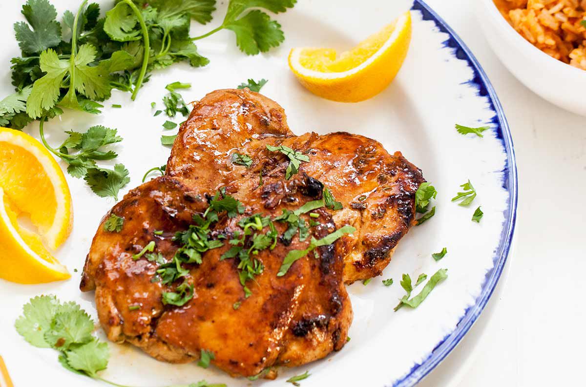 Spicy Orange Marinated Chicken on a plate with lemon wedges and parsley