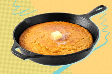 Cast iron skillet of cornbread with a pat of butter in the center on a yellow background
