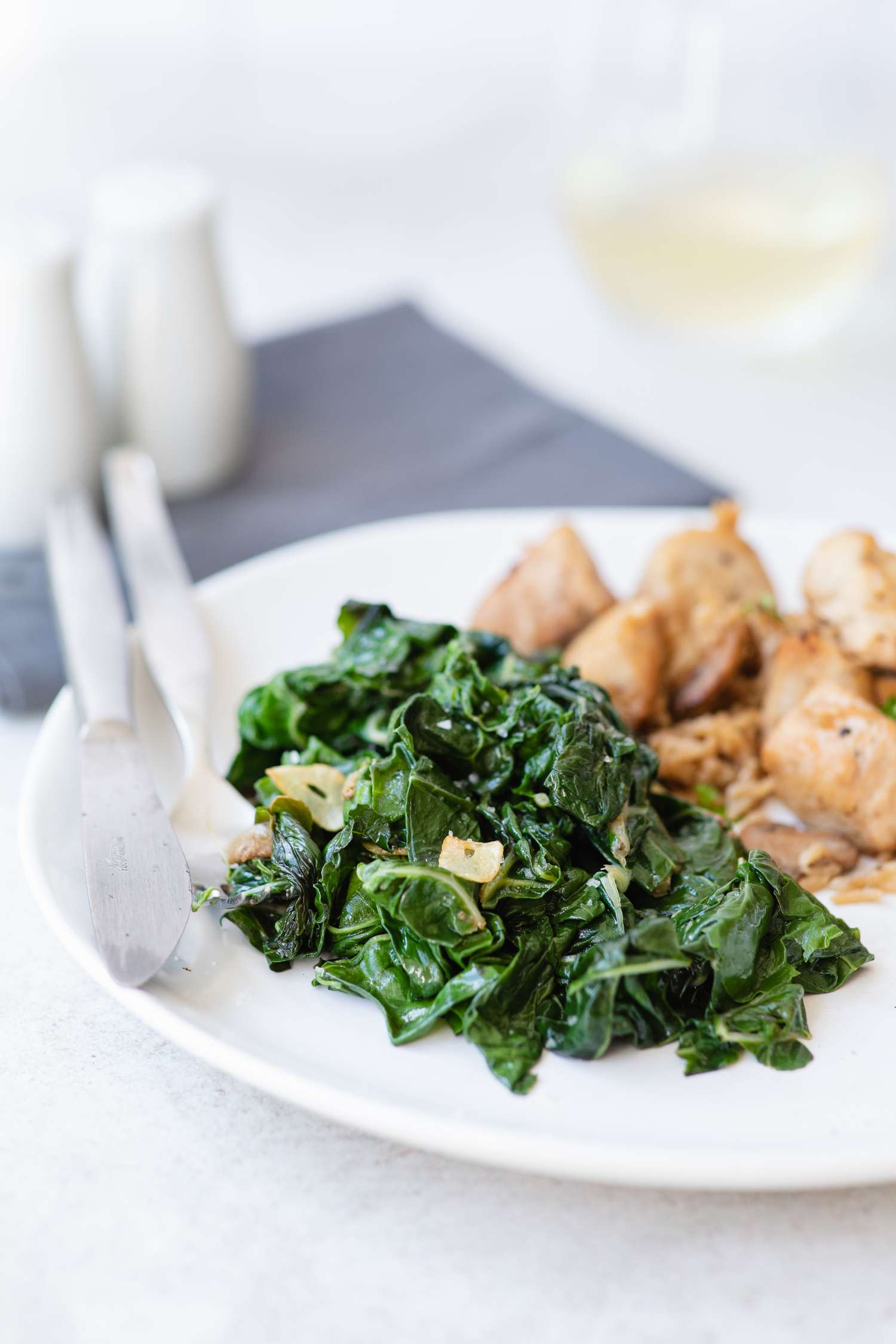 A white plate of sauteed spinach recipe.