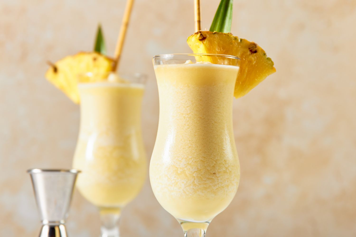 Glasses of PiÃ±a Colada Garnished With Pineapple Wedges, Pineapple Leaves, and a Straw