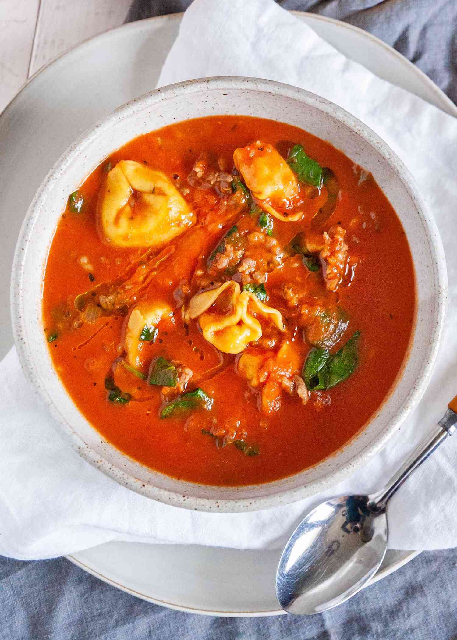 One-Pot Tortellini Soup - white bowl with tomato soup, fresh basil and cheese filled tortellini