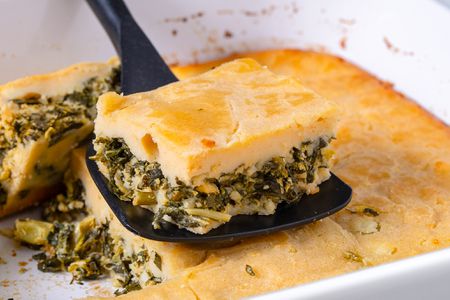 slice of bastaria on a spatula with more in the casserole dish under the spatula