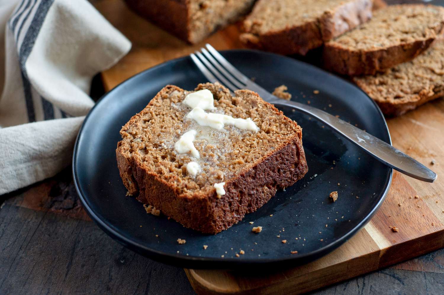 Slice of banana bread with butter on a dark blue plate