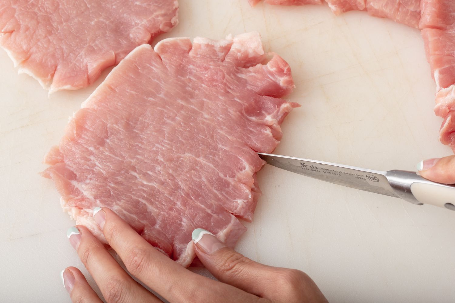 Cutting slits in pork cutlet to make pork schnitzel.