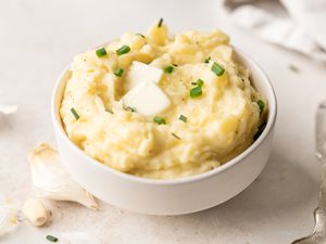 A bowl of roasted garlic mashed potatoes topped with a pat of butter.