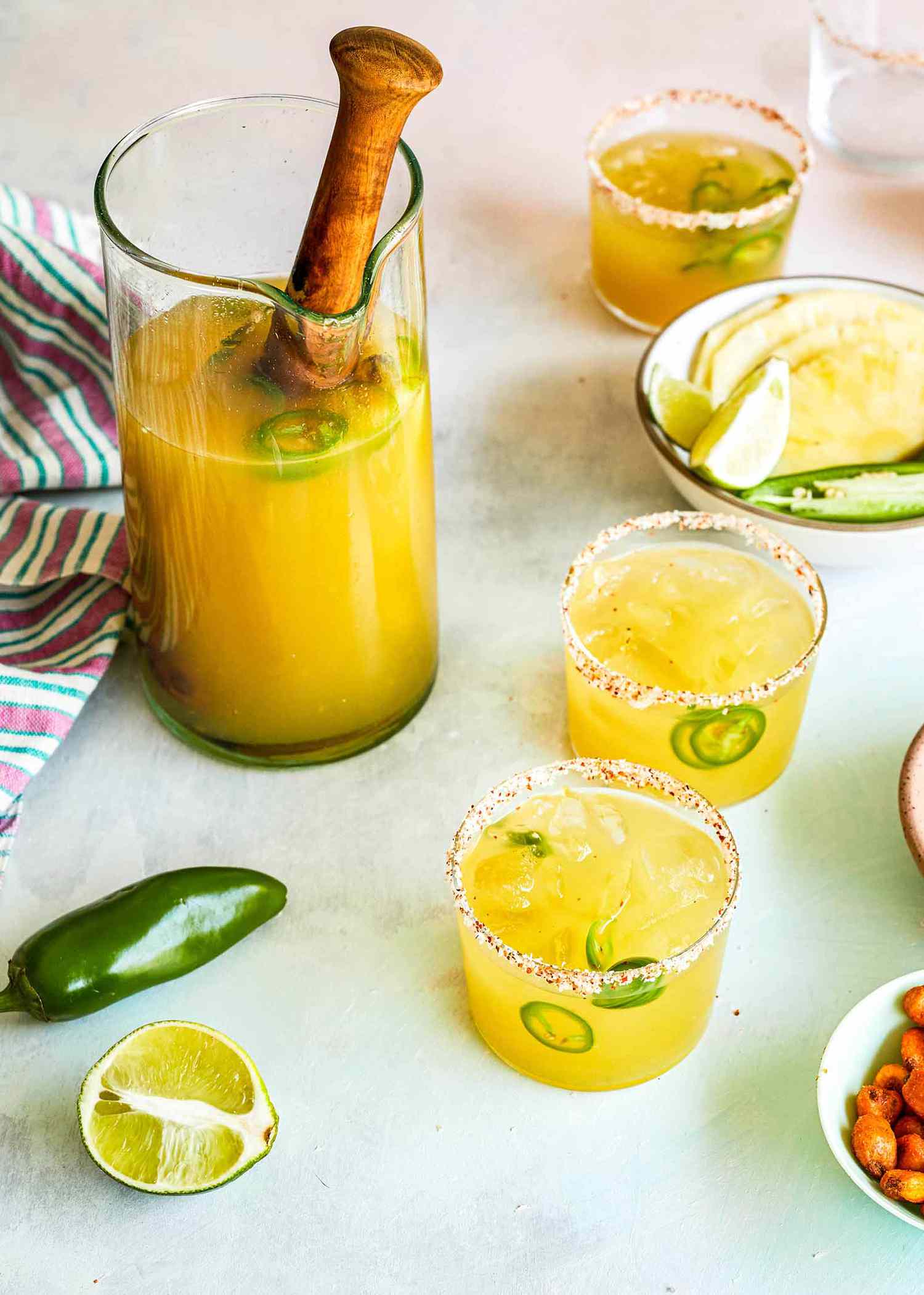 Spicy Pineapple Margaritas in a pitcher with glasses on the side