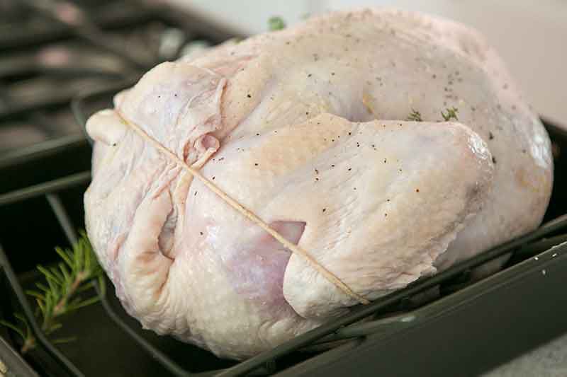 How to cook a turkey by trussing and setting in a roasting pan.