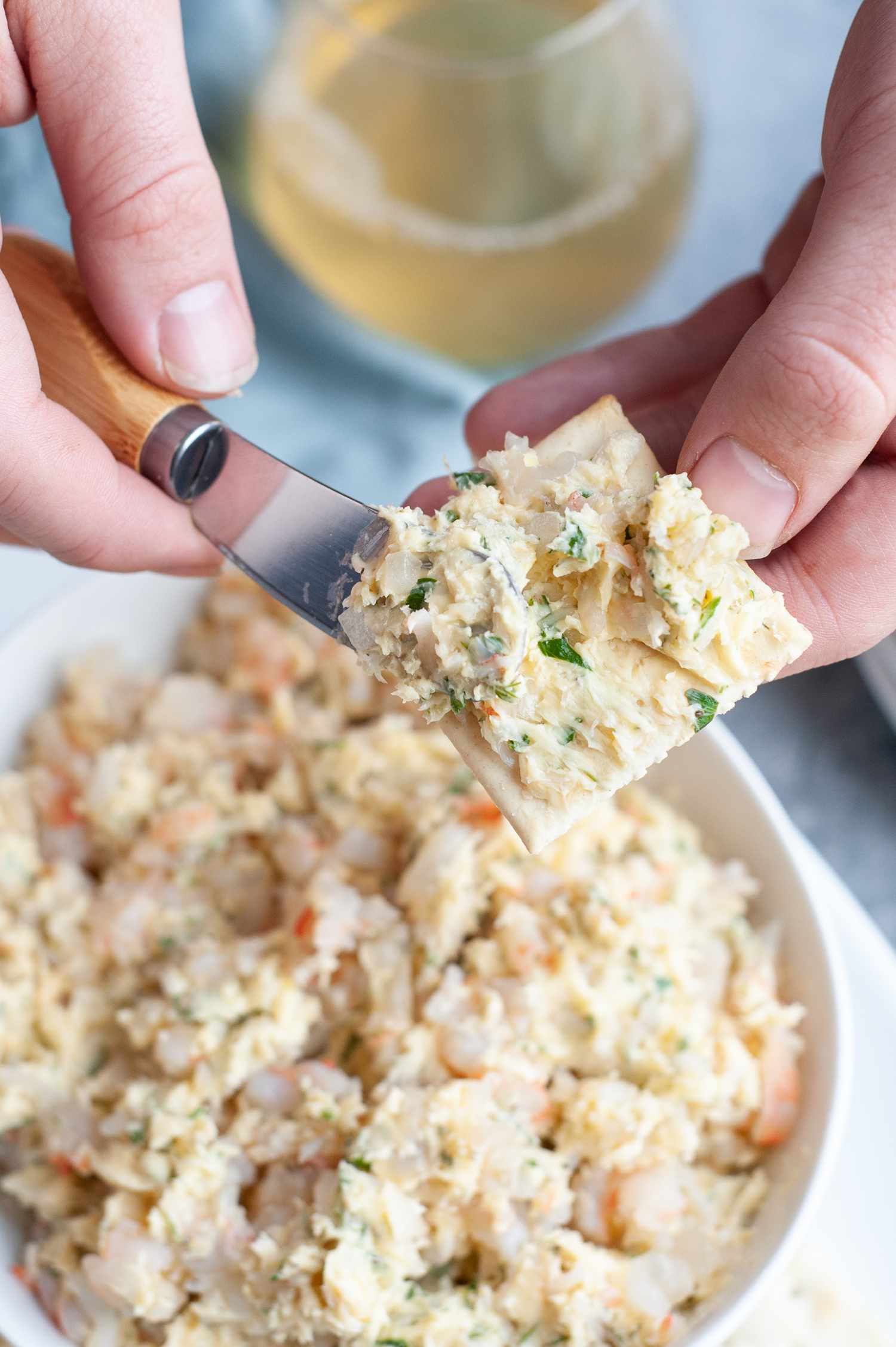 Shrimp Butter Smeared on a Cracker, and in the Background, a Bowl of More Shrimp Butter, a Glass of Wine, and a Kitchen Linen