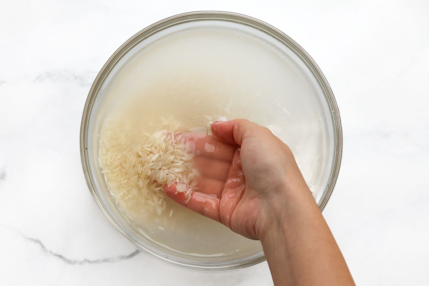 Hand Agitating Basmati Rice in a Bowl of Water for Tahdig Recipe 