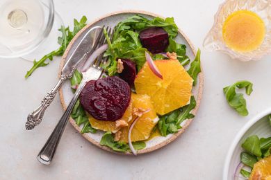 Pouring vinaigrette over a salad of beets and oranges.