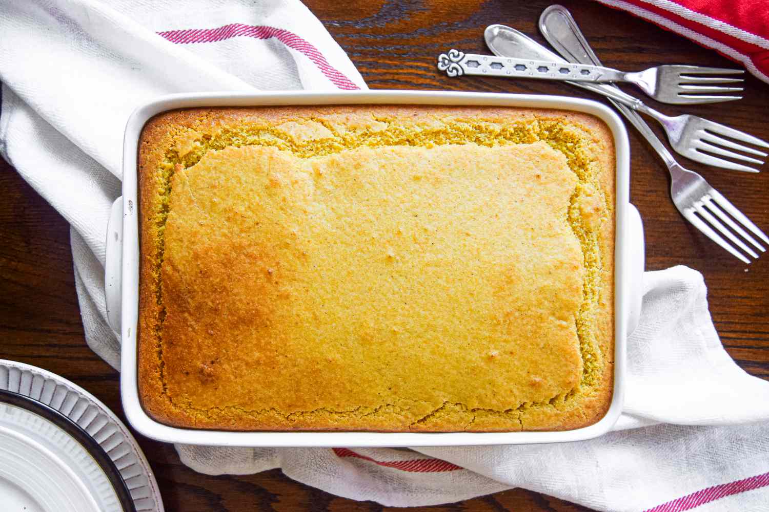 Overhead view of a baked tamale pie with plates and utensils 