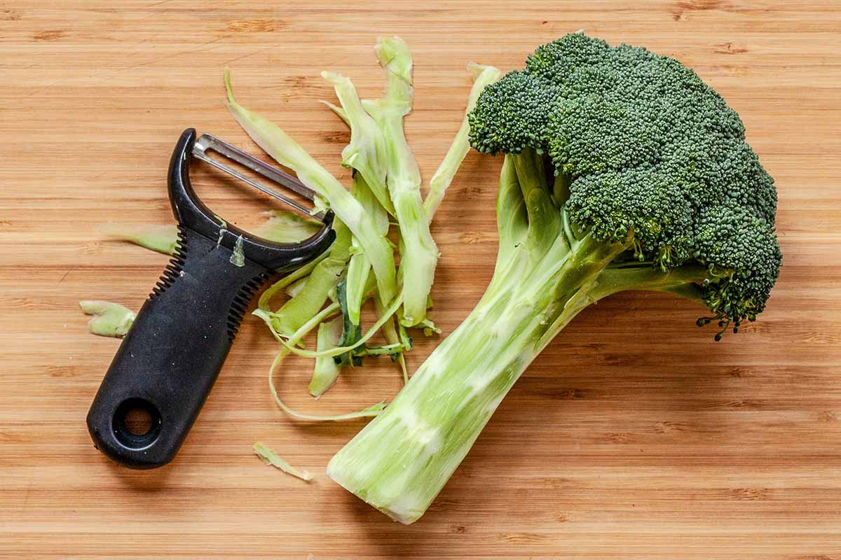Easy Crustless Quiche - broccoli on a cutting board with a vegetable peeler with shavings of the broccoli stock nearby
