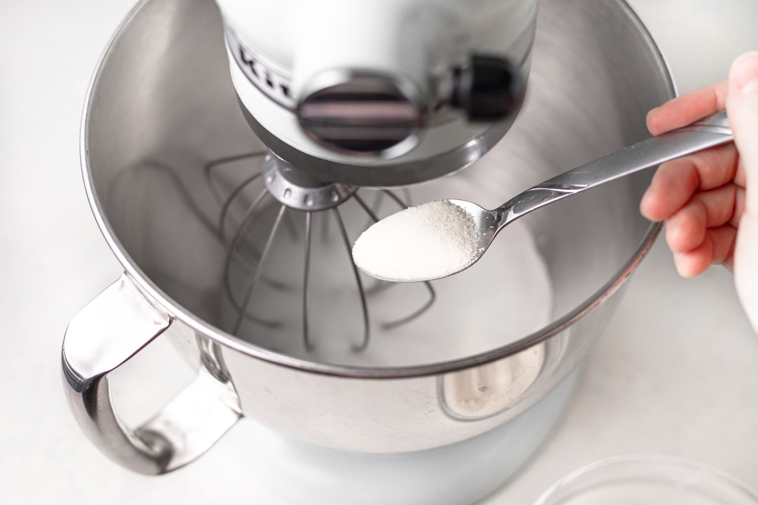 Adding sugar to egg whites in a mixer bowl
