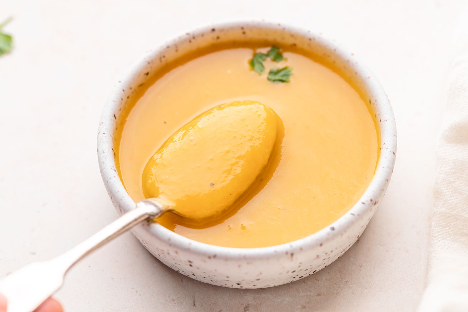 Spooning butternut squash soup out of a bowl.