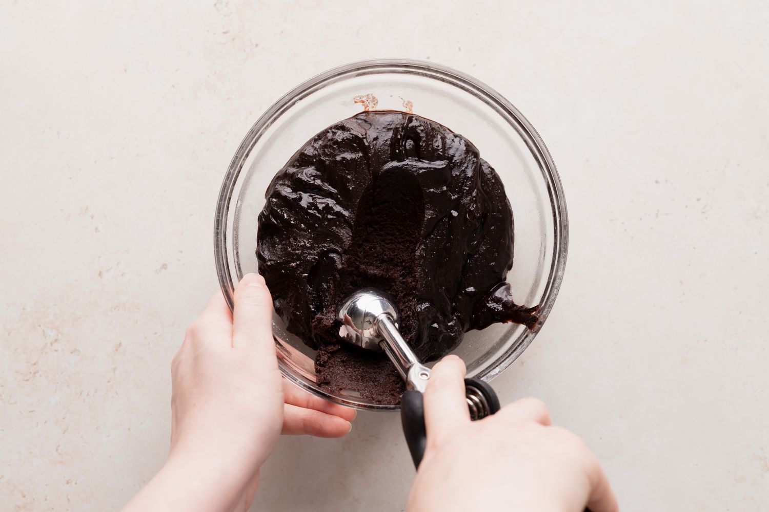 Scooping dough for chocolate crackle cookies with an ice cream scoop.