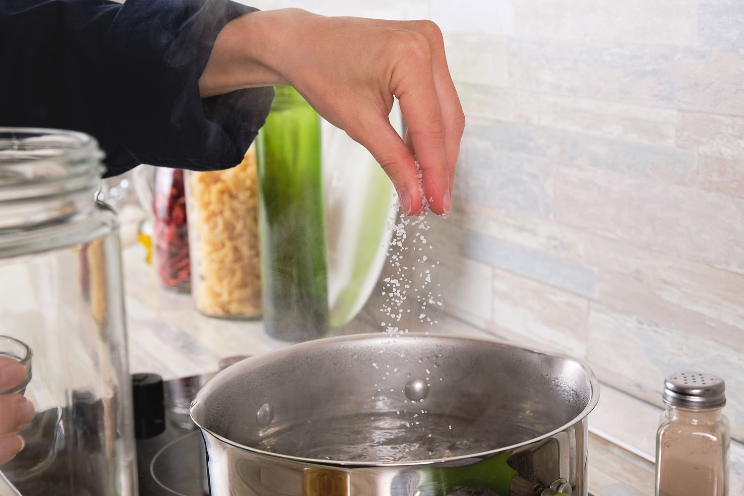 Someone adding salt to a pot of boiling water