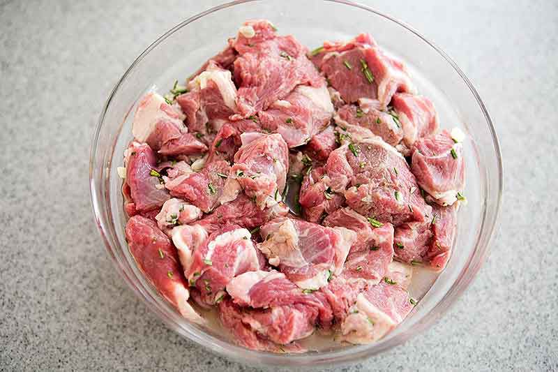 Lamb shoulder marinating in bowl for lamb stew
