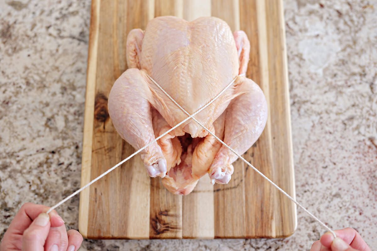 Truss a chicken cross the twine and pull it toward you