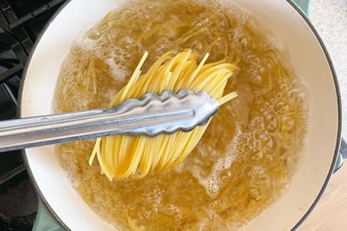 Tongs Lifting Spaghetti from Pot of Boiling Water for No Cook Tomato Sauce Pasta