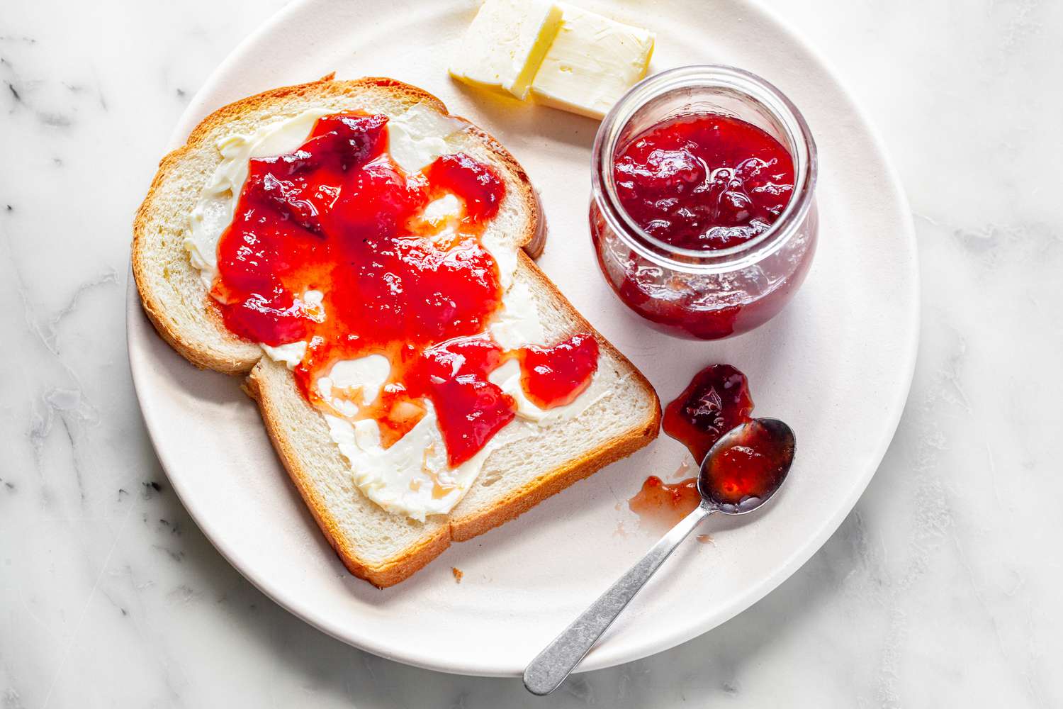 Peach, Pear, and Plum Jam on a Piece of Toast with More in a Jar Next to It
