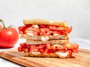 tomato sandwich (cut in half and stacked) on a cutting board