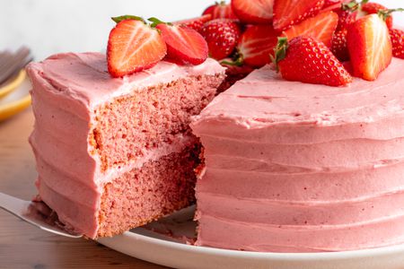 slice of strawberry cake lifted from the rest of the cake using a pie server