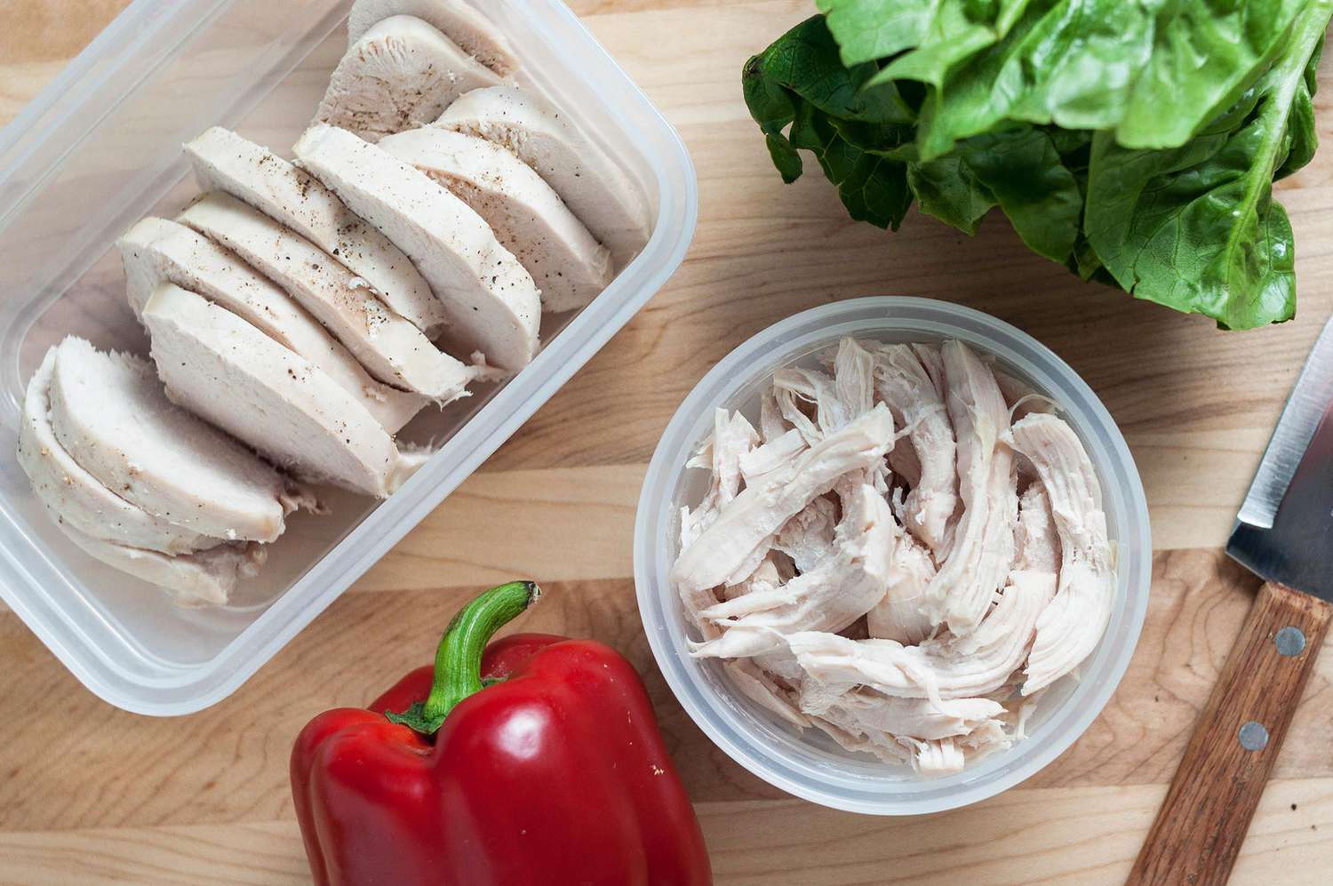 Cooked chicken cut into slices and placed in two plastic containers 
