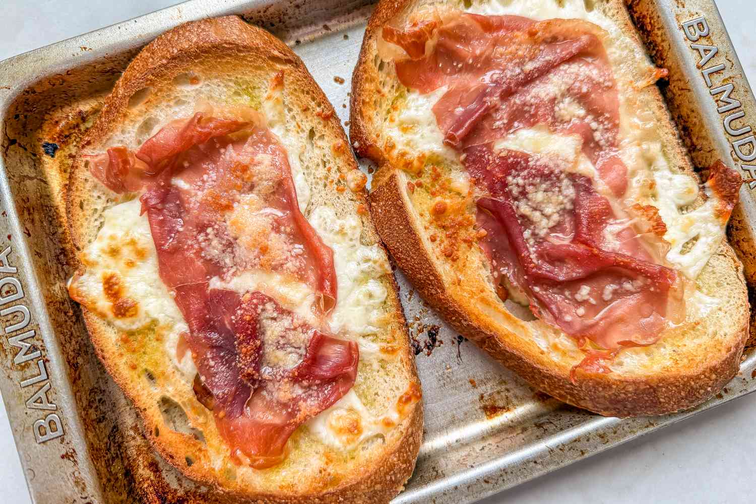 Overhead view of two pieces of toasted ham and cheese toast on a toaster oven tray