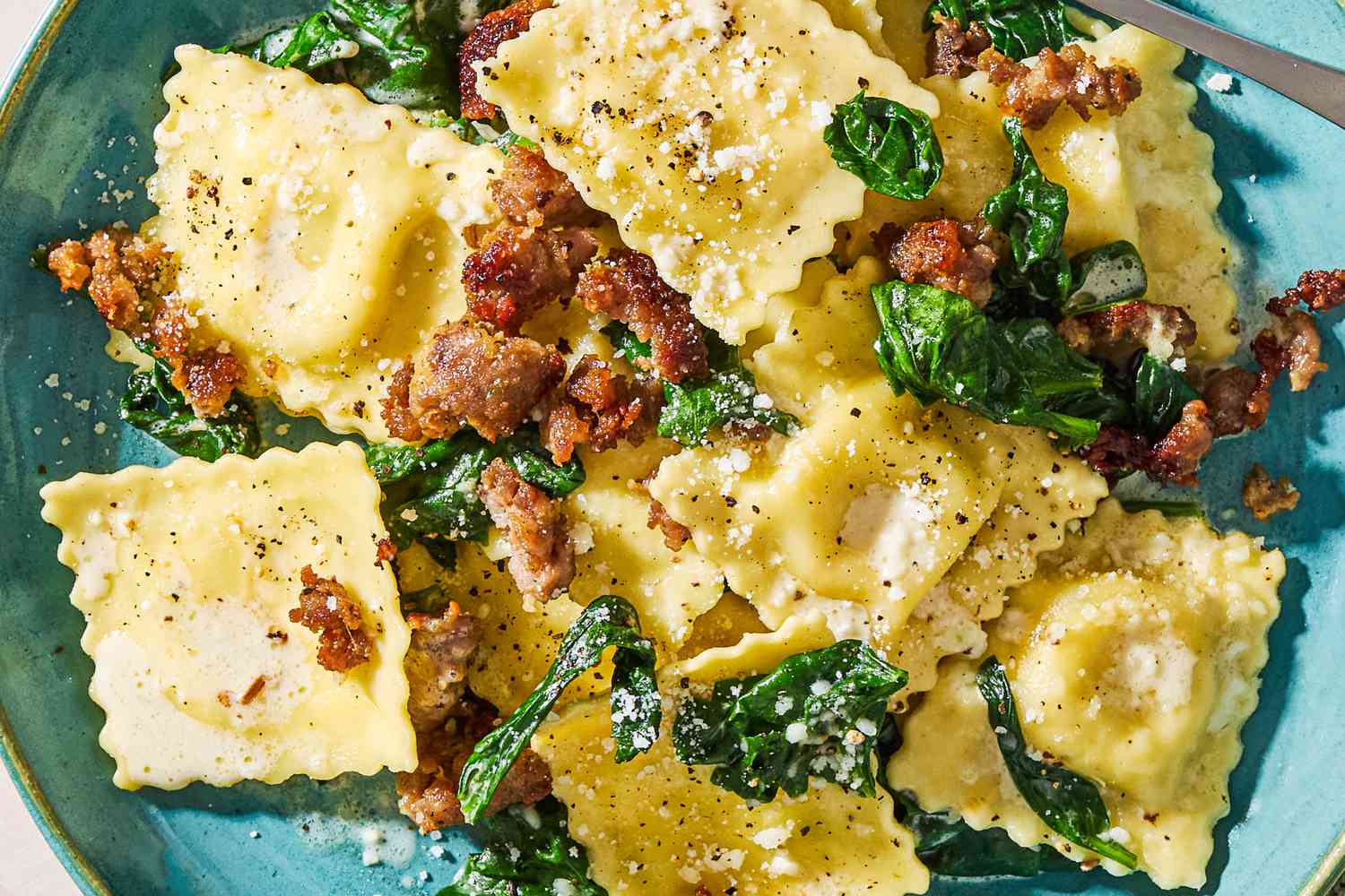 Closeup view of15-minute one-pan ravioli topped with Parmesan cheese in a light blue bowl