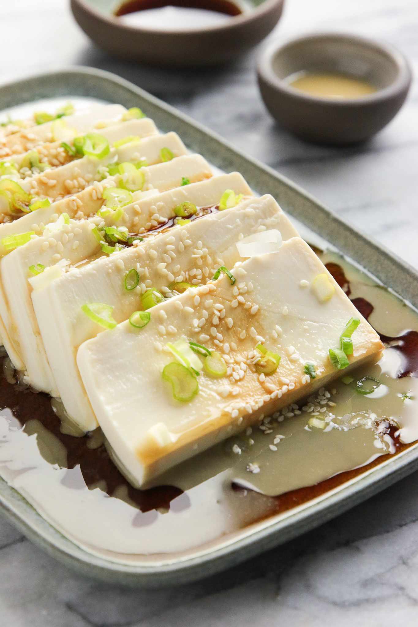 Close Up: Platter of Silken Tofu with Sesame Soy Sauce Next to a Small Bowl with More Soy Sauce and Another Small Bowl with Sesame Sauce