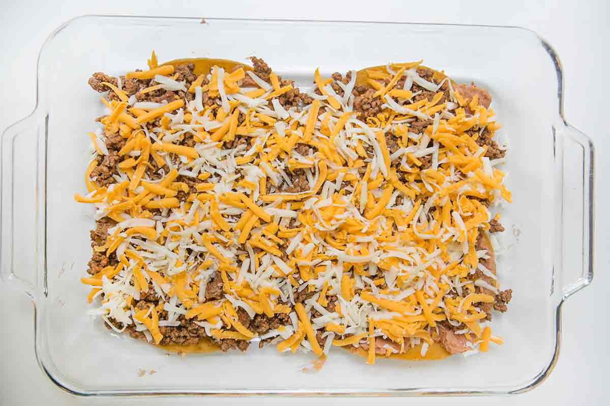 To make mexican lasagna, sprinkle grated cheese over the beef layer