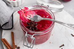 A jar of pickled red onions and a fork set on top with red onions on it.