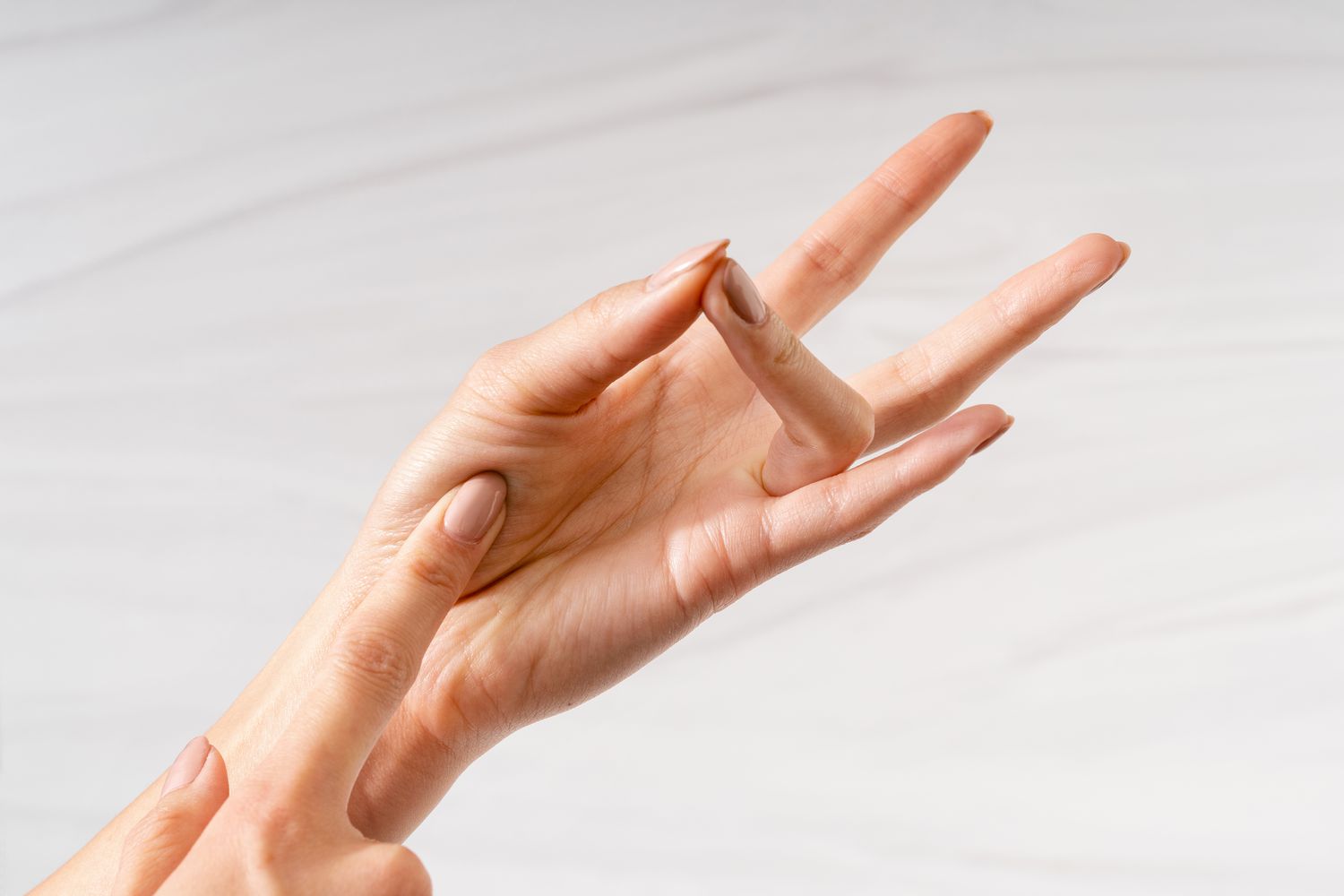 A finger touching the palm of a hand, thumb and rung finger touching, to show medium for The Finger Test to Check the Doneness of Meat