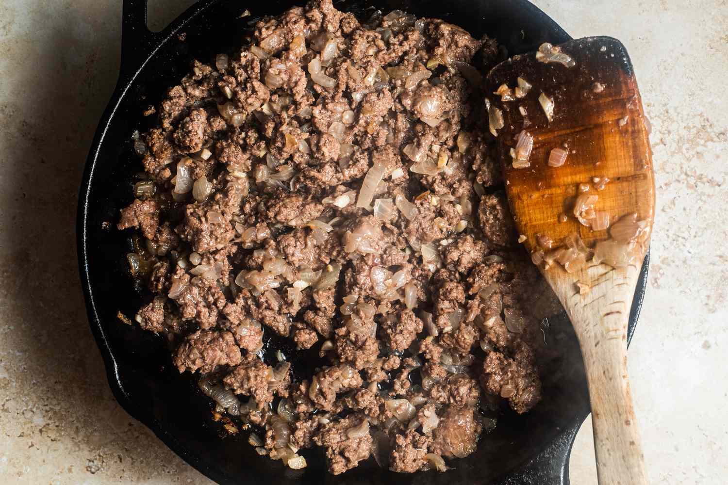 Ground beef cooking with the onions in a cast iron skillet