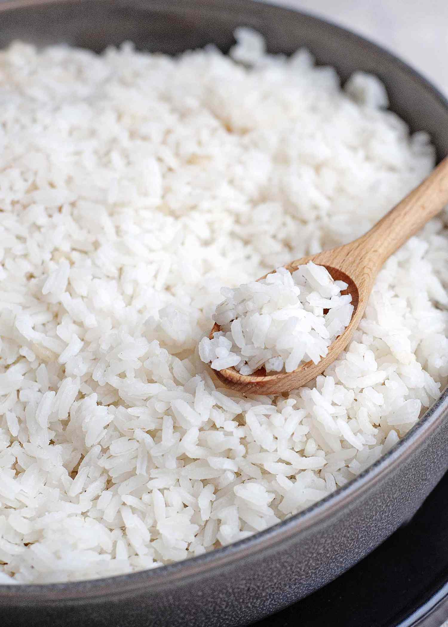 Shallow pan of easy white rice with a wooden spoon full of rice.