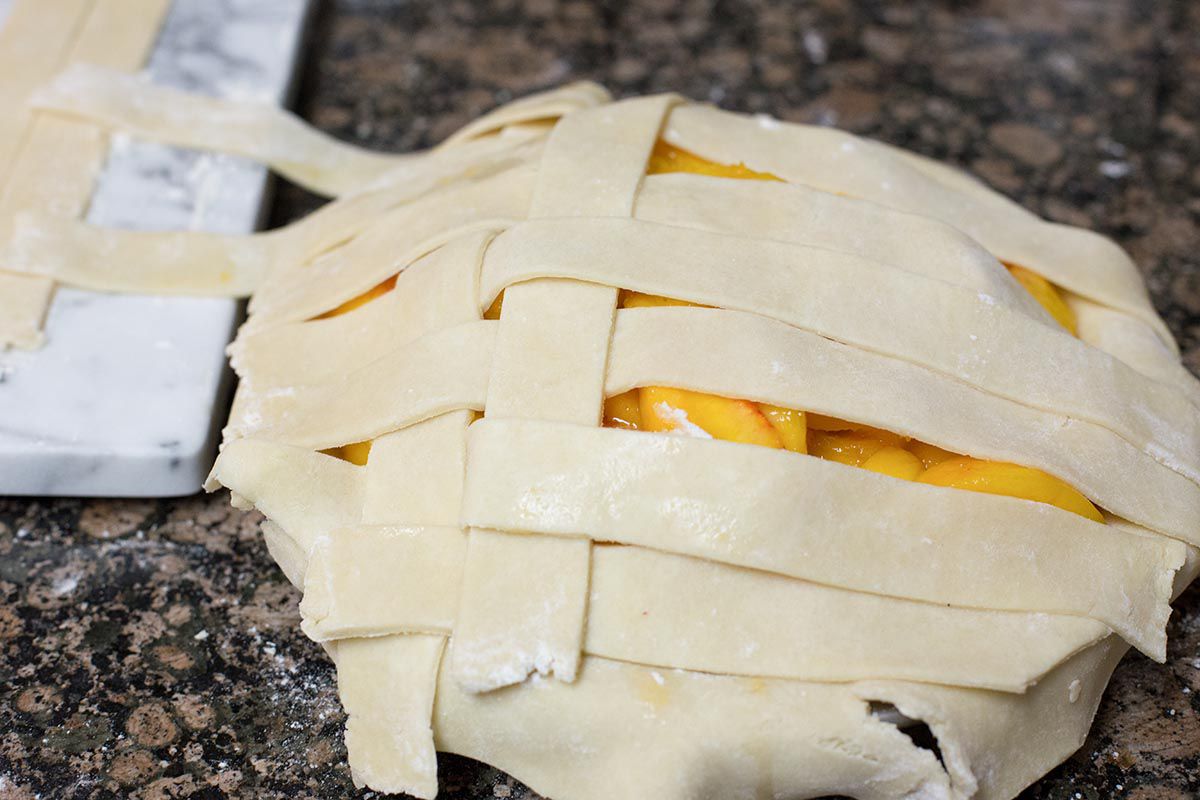 Weave the pie crust strips to make a lattice top for peach pie