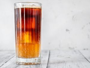 Iced coffee with seltzer in a tall glass, placed on a wooden surface.